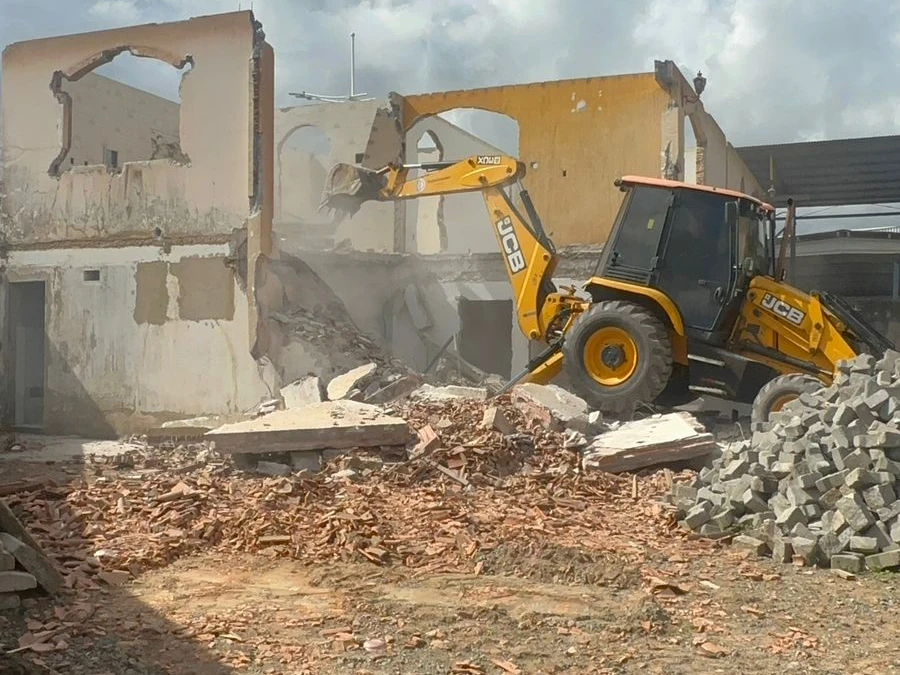 Retroescavadeira JCB em operação durante a demolição de uma estrutura